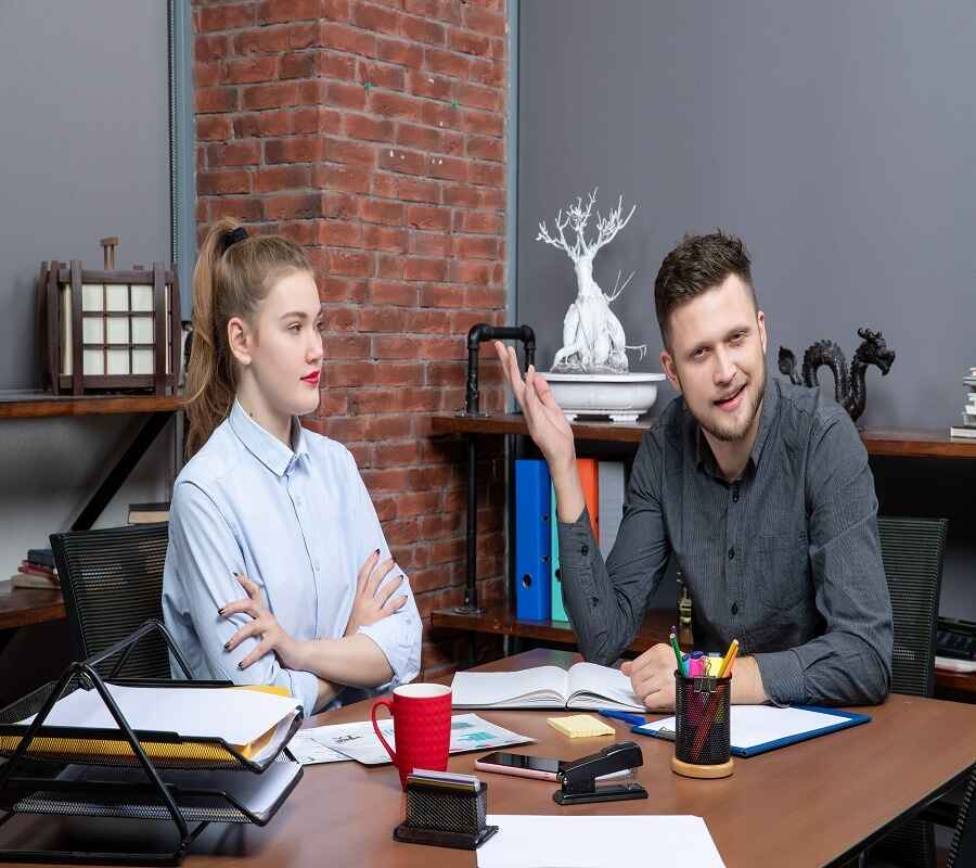 Business coaching session in a modern office with a male coach explaining a point to a focused female client.