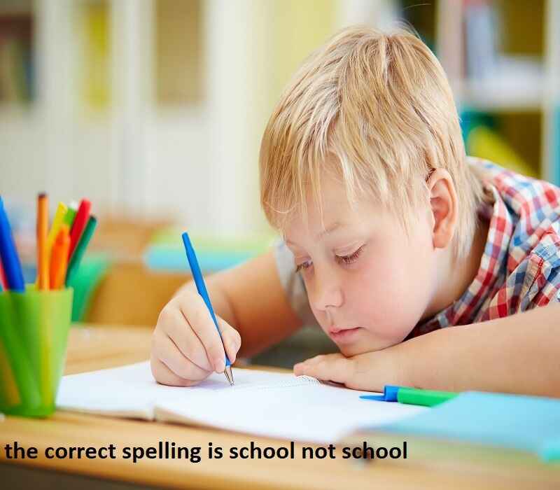 A young boy is focused on writing in a notebook at a desk, surrounded by colorful pencils. The text overlay reads, "the correct spelling is school not school."